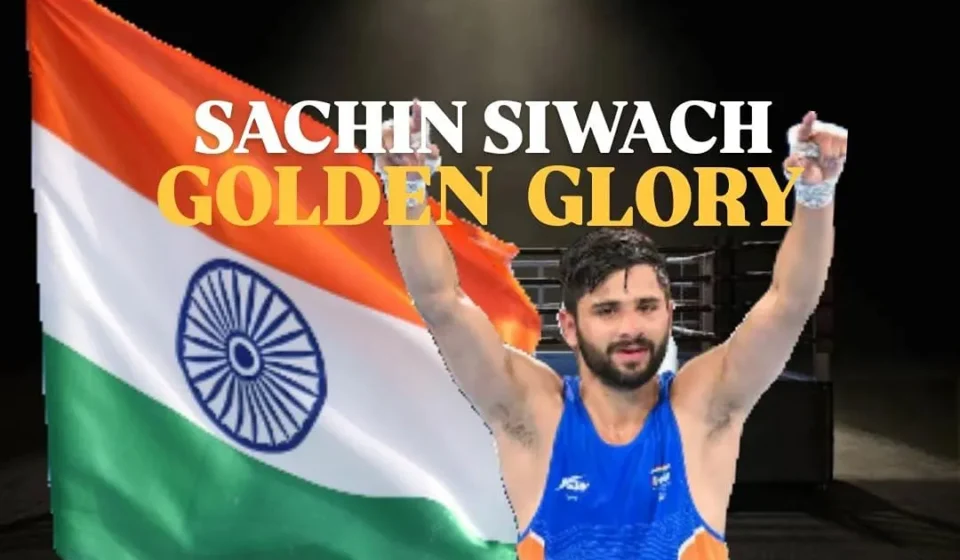 Sachin Siwach Gold celebration after winning the men's 60 kg boxing title at the Glasgow 2026 Commonwealth Games, posing with raised arms in front of the Indian flag.